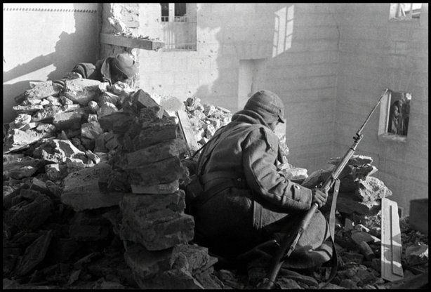 TERUEL, Spain—Republican soldiers in a destroyed building on the lookout for Nationalist soldiers, December 1937. © ROBERT CAPA © 2001 By Cornell Capa / Magnum Photos